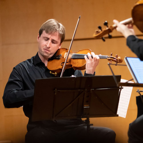 A musician on stage playing a violin