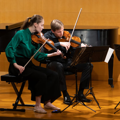 Two musician on stage playing violins