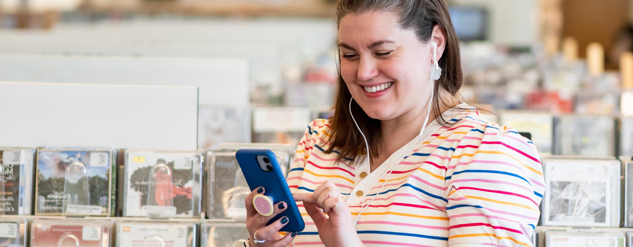 A person listening to music on their phone in the CD area of the library