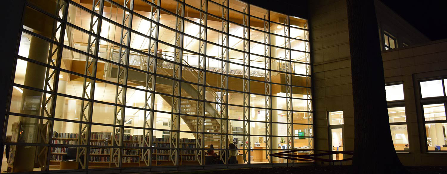 Greenwich Library's glass facade illuminated at night.